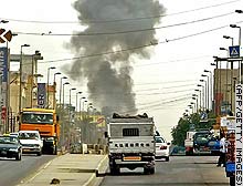 [ Smoke rises above Baghdad from a car bomb explosion [18Mar06] that wounded two people. ]